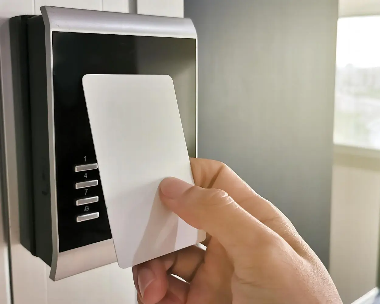 Access card being presented to a wall mounted card reader with keypad