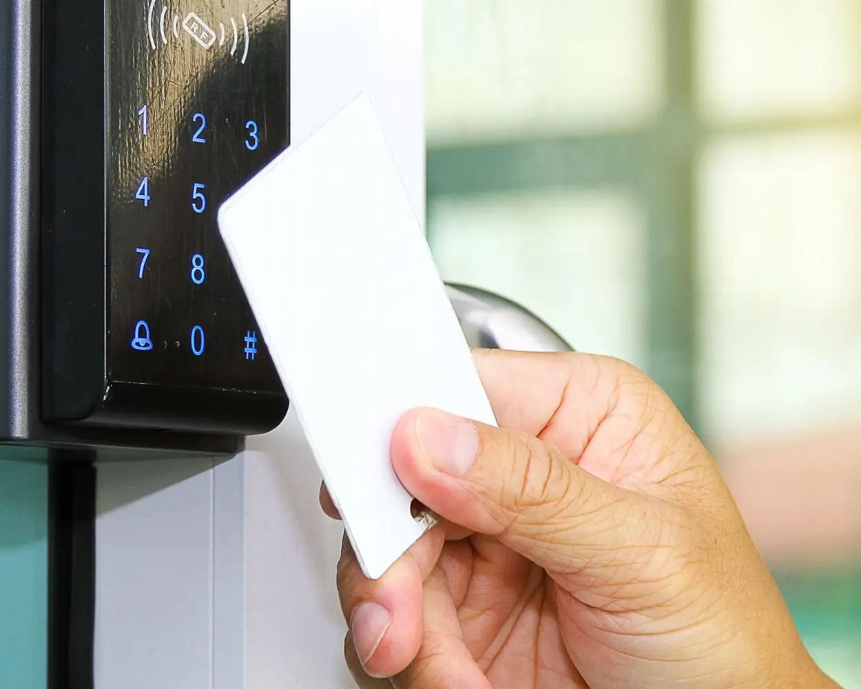 Card being tapped on a keypad access control reader beside a glass door