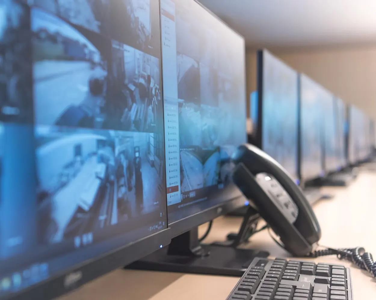 Desk lined with monitors showing live CCTV camera feeds