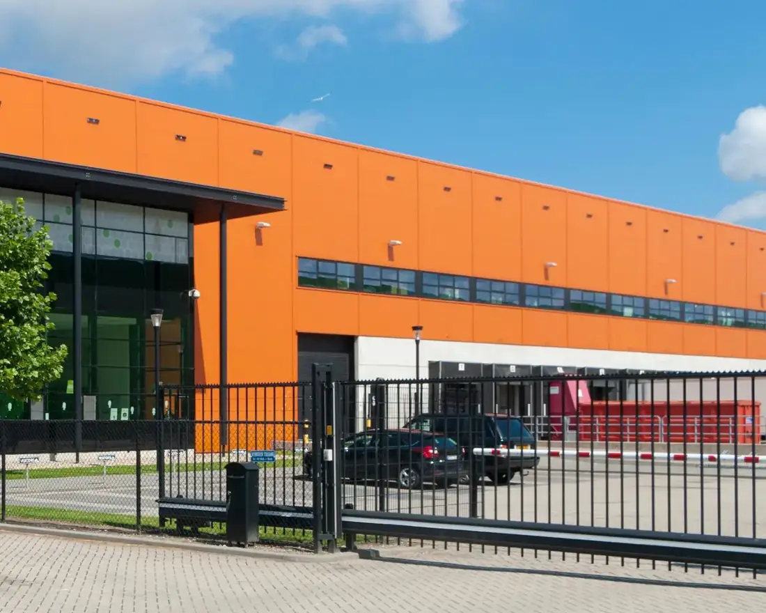 Commercial warehouse building with a steel sliding security gate at the yard entrance
