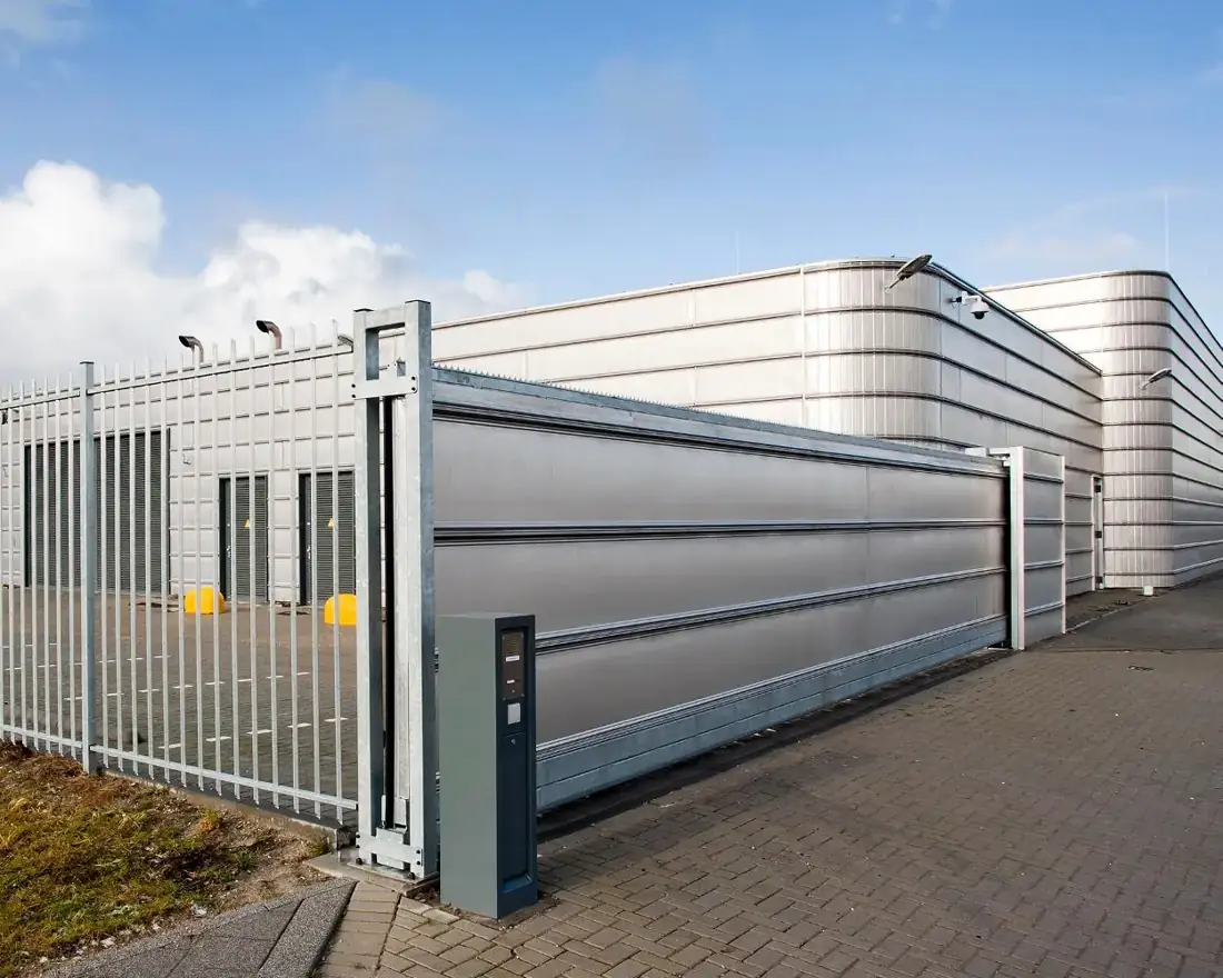 Automatic sliding gate and mesh security fencing outside a modern commercial building
