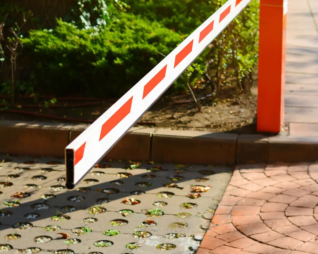 Red and white automatic rising arm barrier across a vehicle entrance